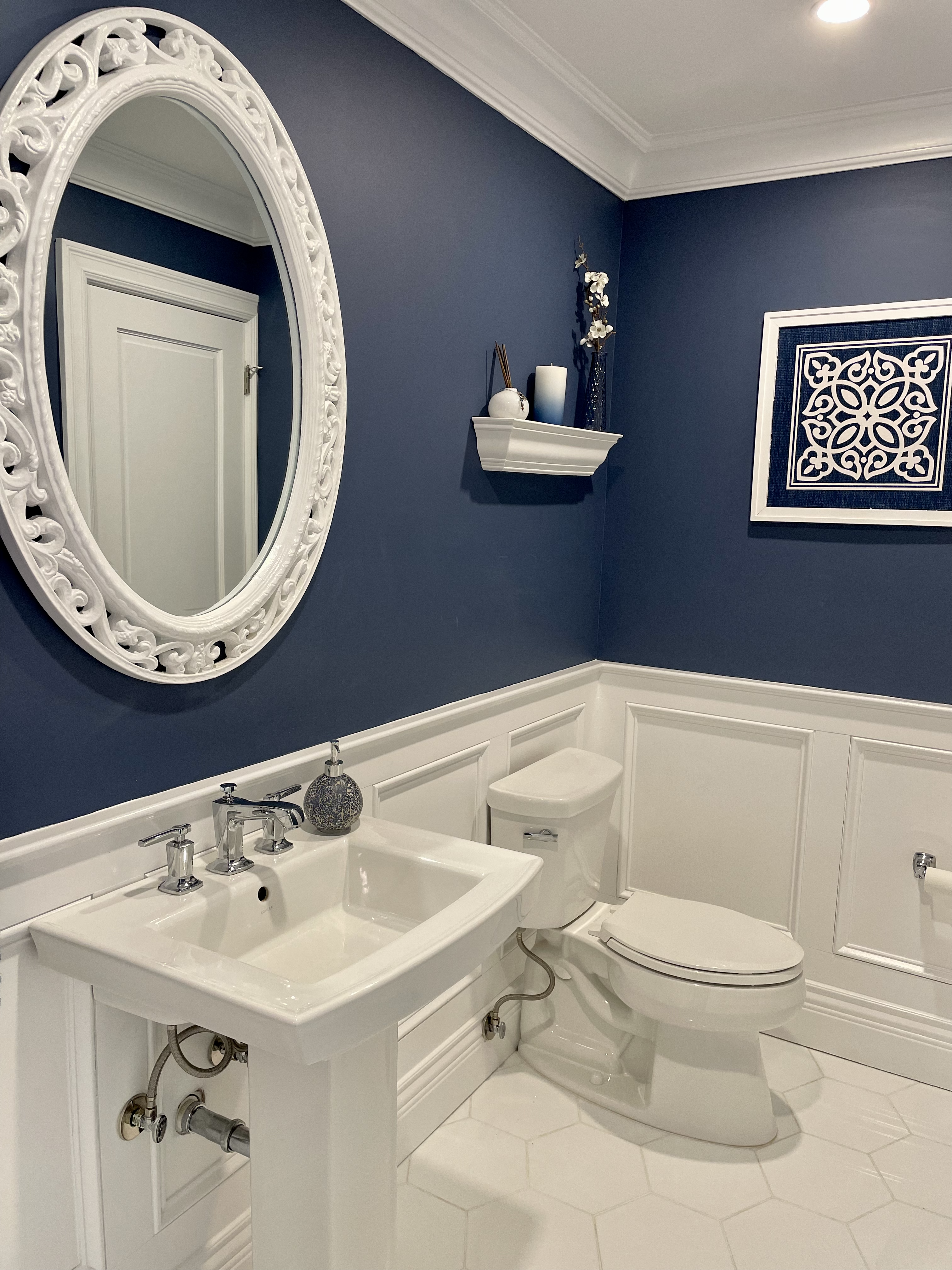 Elegant bathroom with navy walls, white fixtures, and decorative accents.