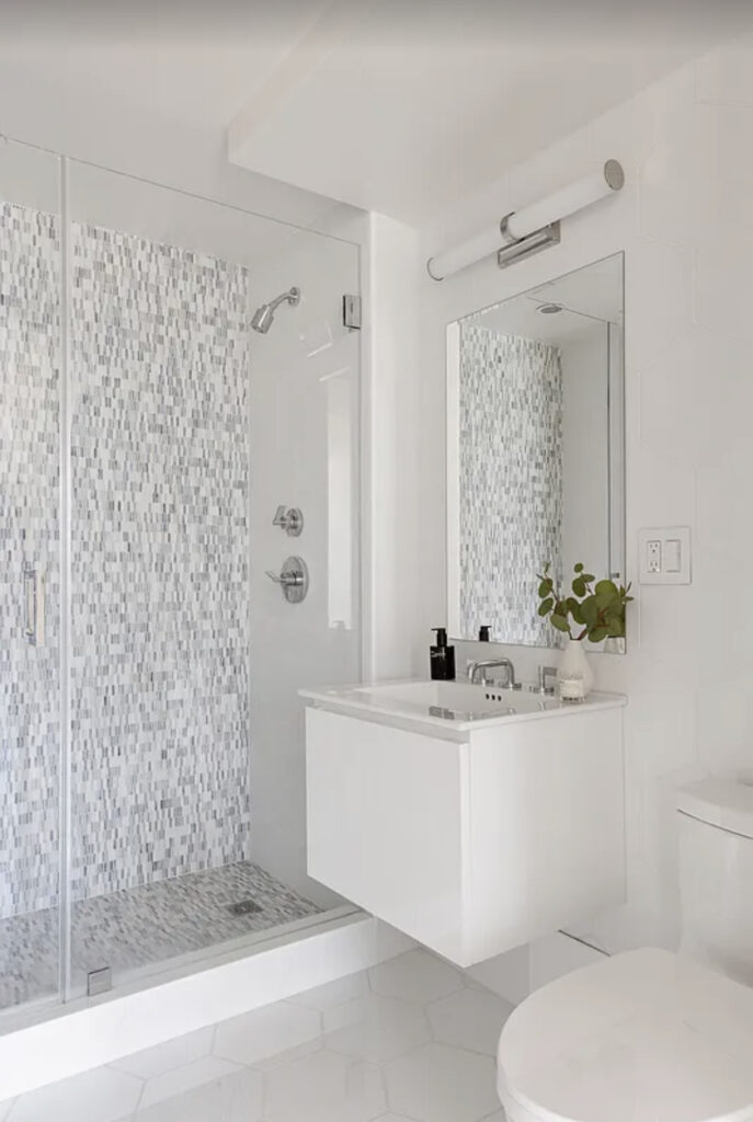 Minimalist white bathroom with patterned shower curtain and wall-mounted sink.